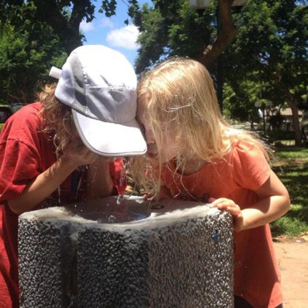 Picture of two little girls drinking out of a water fountain.