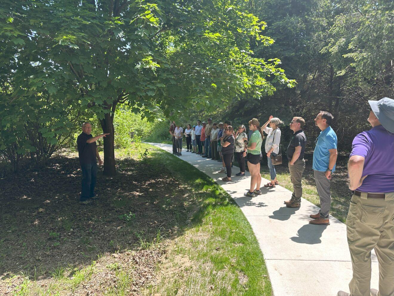 Participants of ribbon cutting ceremony walk through arboretum.