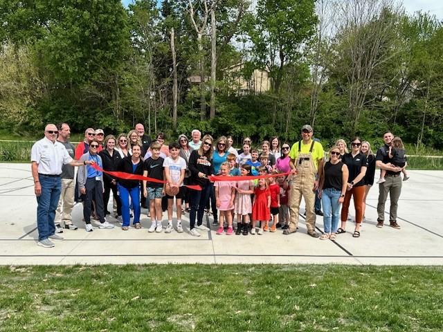 Representatives from the City of Fort Calhoun, Papio NRD, and community members holding a red ribbon for ceremony.
