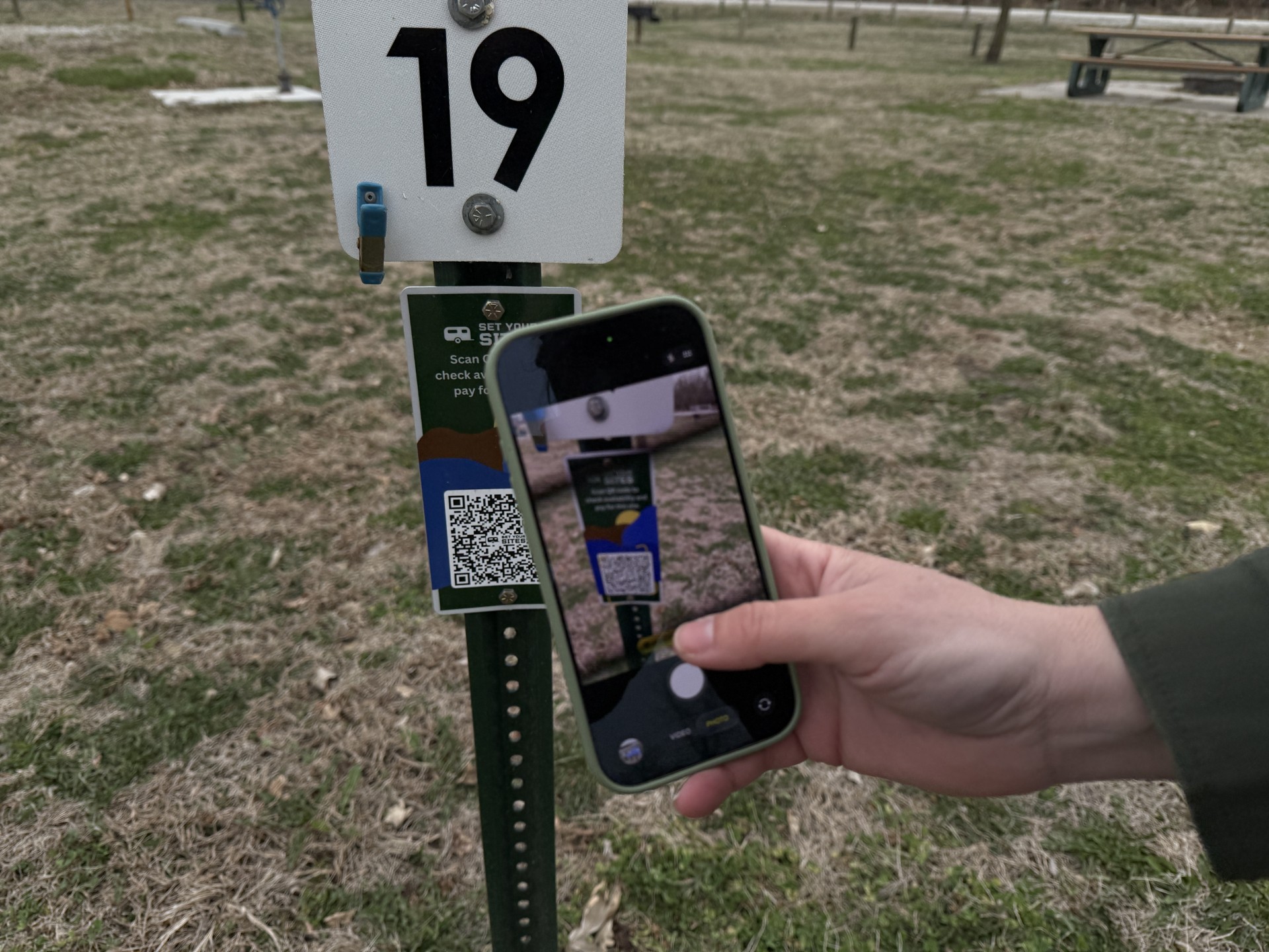 Picture of a mobile phone scanning a QR code at a campsite.